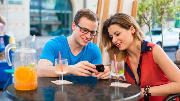 Young couple with mobile phone in cafe — Stock Photo, Image