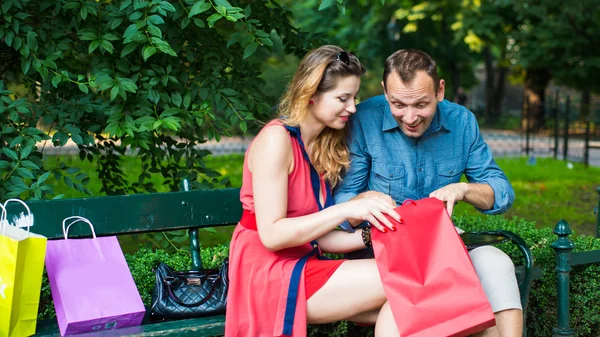 Couple sitting on bench with bags — Stock Photo, Image