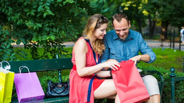 Pareja sentada en el banco con bolsas — Foto de Stock