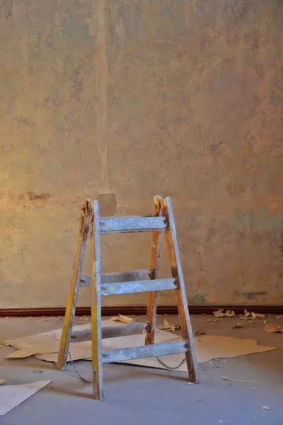 Torn wallpaper and a wooden ladder — Stock Photo, Image