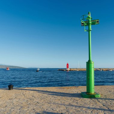 Hırvatistan 'ın Adriyatik Denizi kıyısındaki Krk limanında bir iskelede yeşil deniz feneri                               