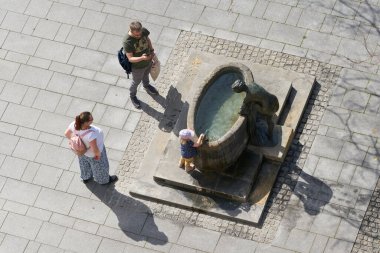 Magdeburg, Almanya 29 Nisan 2022: Çocuklu aile yazın Almanya 'nın Magdeburg şehir merkezinde bir çeşmede serinlemek istiyor                               