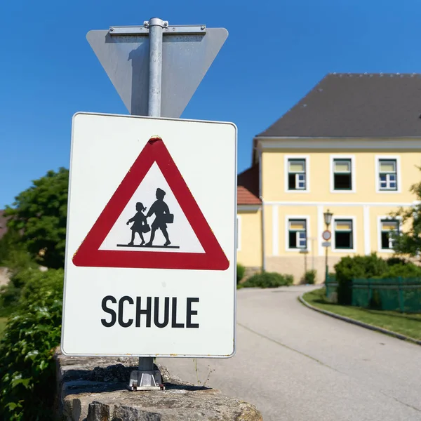 Danger sign indicating possible school children in the road area in the municipality of Emmersdorf in Austria. Translation on the sign: School