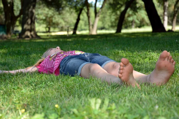 Jong meisje tot in het gras glimlachen — Stockfoto