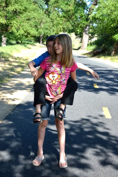Brother catching a ride on sister's back — Stock Photo, Image