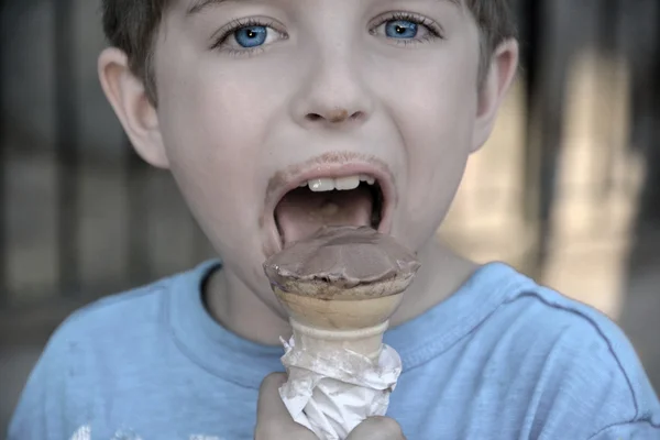 Boy with dirty chocolate face eating ice cream
