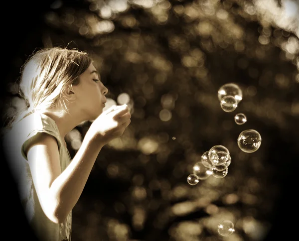 Giovane ragazza soffiando bolle in parco — Foto Stock