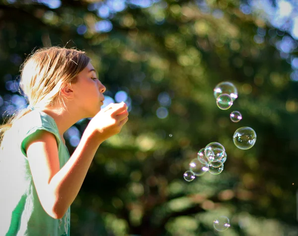 Giovane ragazza soffiando bolle in parco — Foto Stock