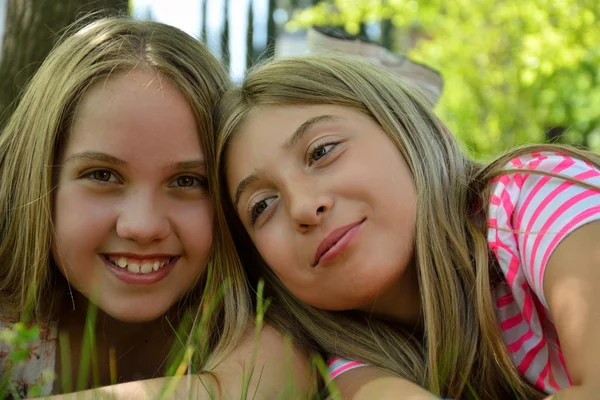 Two girls sitting in grass smiling — Stock Photo, Image