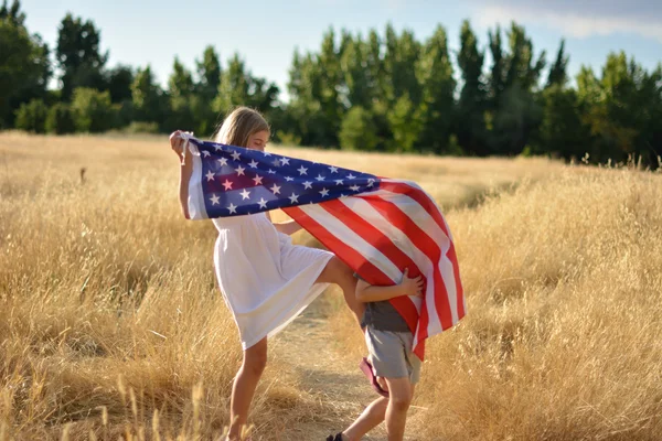 Boy and girl playing holding American flag banner — Stock Photo, Image