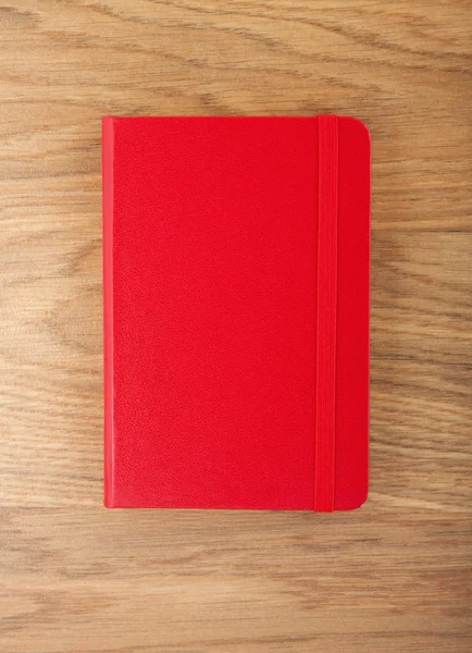 Copybook rojo con banda elástica sobre fondo de madera . —  Fotos de Stock