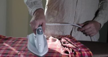 Erkek elleri ütü masasında ütülü giysiler.