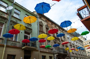 Gri gökyüzüne karşı renkli şemsiyeler.