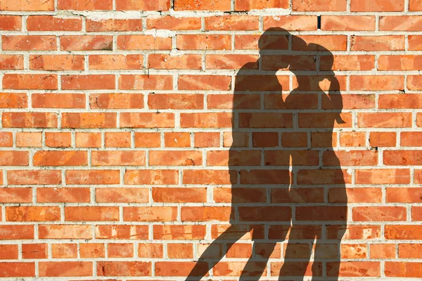 Kissing silhouette couple against red brick wall — Stock Photo, Image