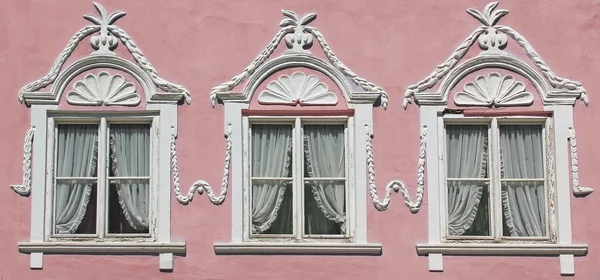 Três janelas na parede da casa rosa com estuque ornamentado — Fotografia de Stock