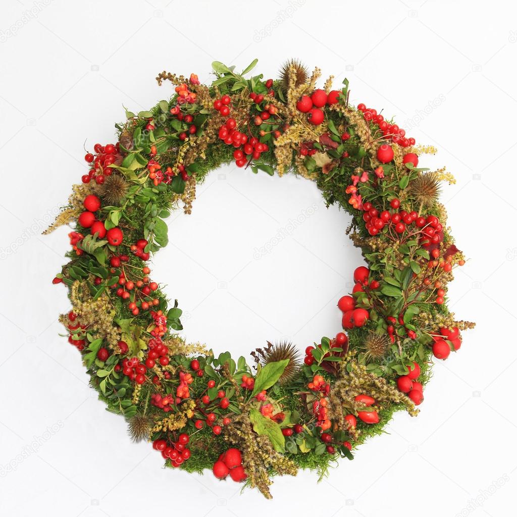 Decorative autumn wreath with moss, berries and tiny apples