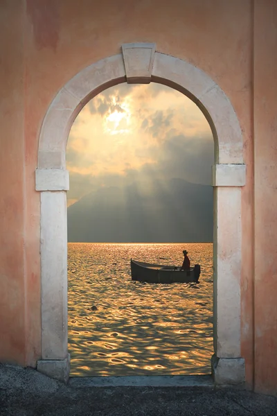 Zobacz poprzez łukowate drzwi łódź wiosłowa o zachodzie słońca — Zdjęcie stockowe