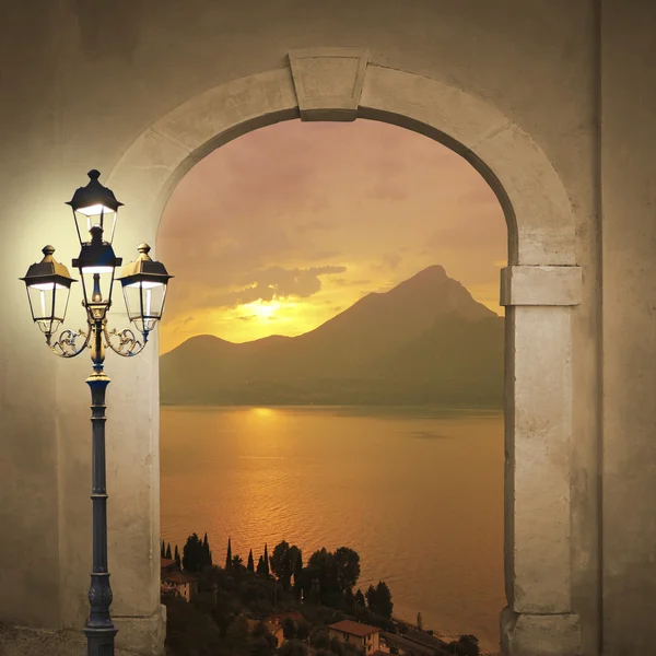 Arched door with view to sunset landscape, romantic mood with burning lantern
