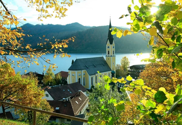 Autumnal view through branches to schliersee lake and church — Stock Photo, Image