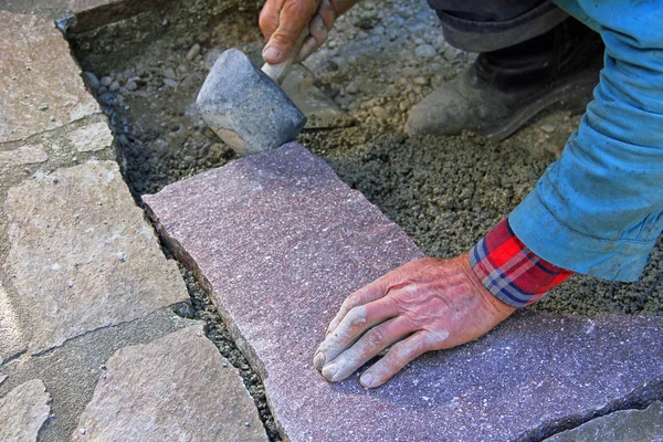 Senior landscape gardener fitting a flagstone tile with a rubber — Stock Photo, Image