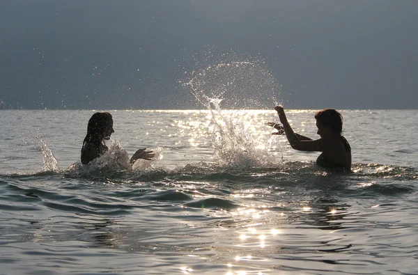 Adolescentes de pie en el agua y chapoteando entre sí, en —  Fotos de Stock