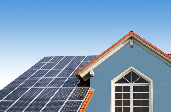 Современный новый дом, крыша с солнечными батареями, голубой фасад — стоковое фото