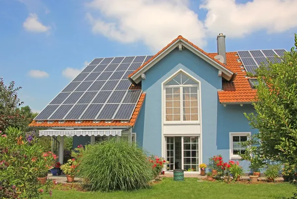 Moderna casa e giardino di nuova costruzione, tetto con celle solari, blu Immagine Stock