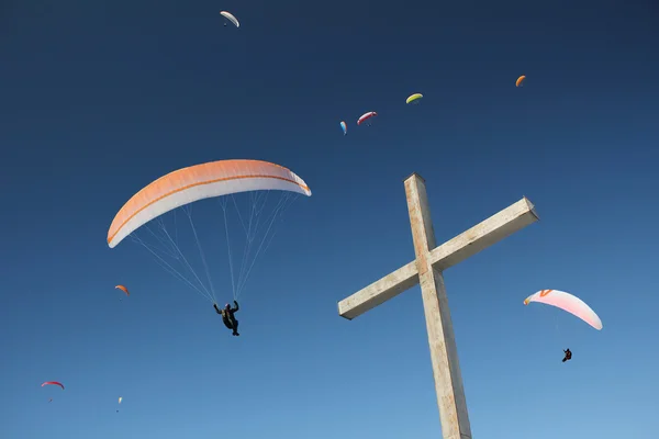 Groupe de parapentes, flottant au-dessus de la croix de montagne — Photo