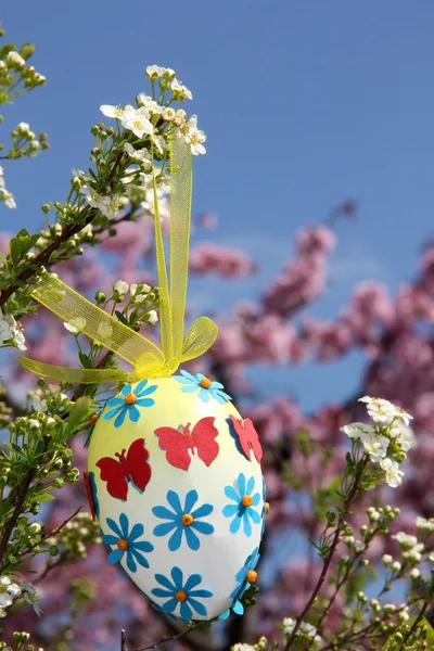 Easter egg with paper flowers, hanging in a shrub — Stock Photo, Image