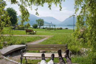 Spa bahçesinde dinlenmek ahşap bir bankta Schliersee, ilkbaharda söğüt dallarının arasından görmek