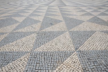 Üçgen desenli gri tonlarda kaldırım taşları, granit küplerden yapılmış tarihi sokak yüzeyi.