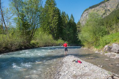 Nehir yatağındaki çıplak ayaklı adam baharda soğuk nehirde sertleşti, allgau alpleri