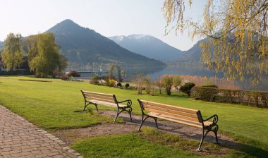 Spa Garden Schliersee 'de iki banklı bir eğlence yeri. Baharda göl manzarası ve Bavyera Alpleri.
