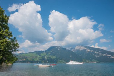 passenger liner and sailboats at lake Thunersee. Niederhorn mountain switzerland. blue sky with cumulus cloud heaps.