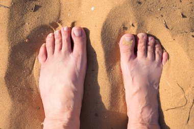 female feet barefoot in the sand. detail shot