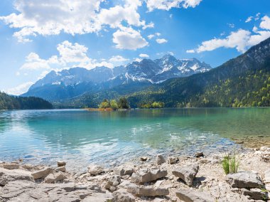 rocky bathing beach at lake shore Eibsee, view to Zugspitze mountain, upper bavarian landscape in summer