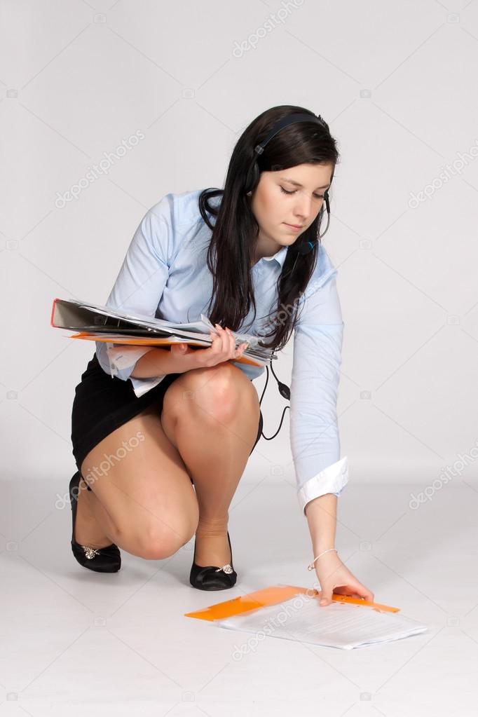 Young woman in mini skirt and blouse, squatting rises from the g