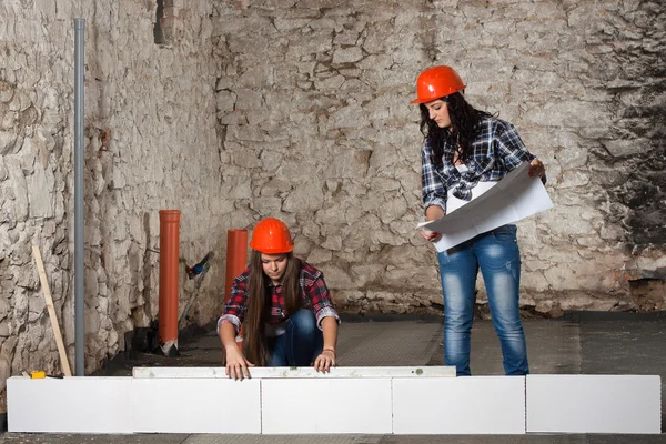 Two young long-haired woman built a new wall from blocks — Stock Photo, Image