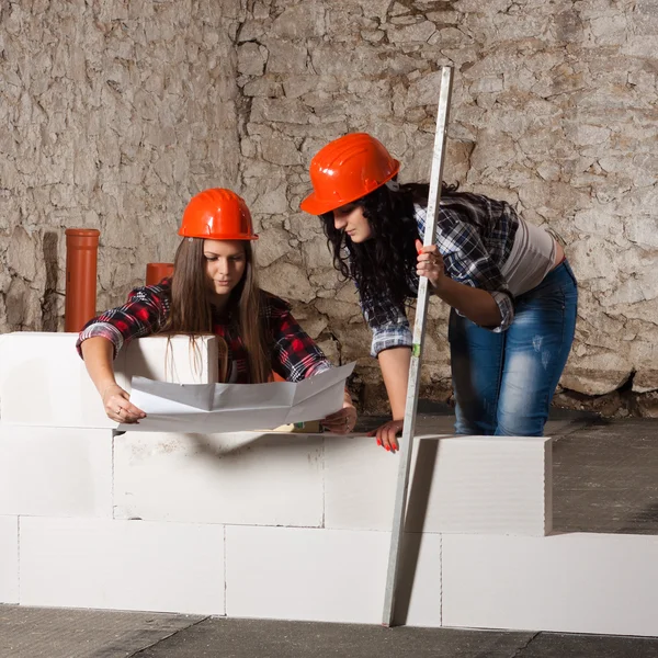 Two young long-haired woman built a new wall from blocks — Stock Photo, Image