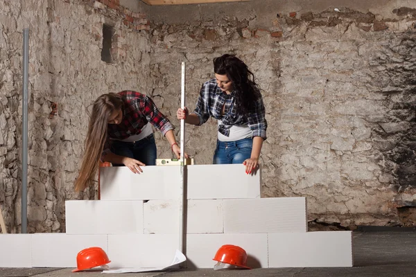 Two young long-haired woman built a new wall from blocks — Stock Photo, Image