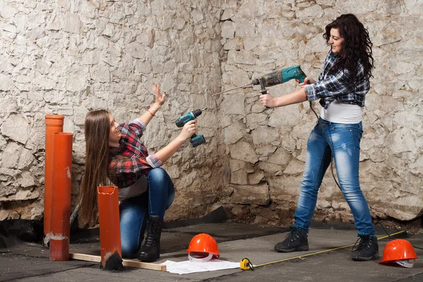 Zwei junge langhaarige Frau mit einem Bohrer und Schraubenzieher — Stockfoto