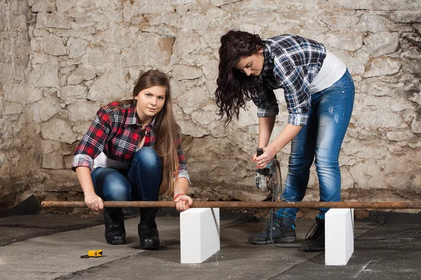 Deux jeunes femmes aux cheveux longs avec une meuleuse d'angle — Photo