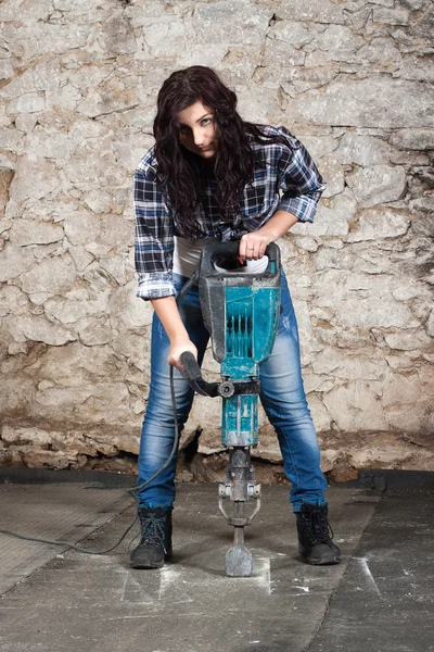 Jovem mulher de cabelos longos com um martelo pneumático — Fotografia de Stock