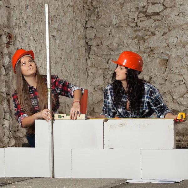 Två unga långhåriga kvinna byggde en ny mur från block — Stockfoto