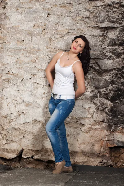 Jeune femme aux cheveux longs au vieux mur de pierre — Photo