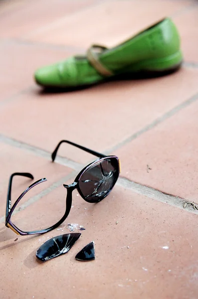 Kaputte Sonnenbrille und grüner Schuh — Stockfoto