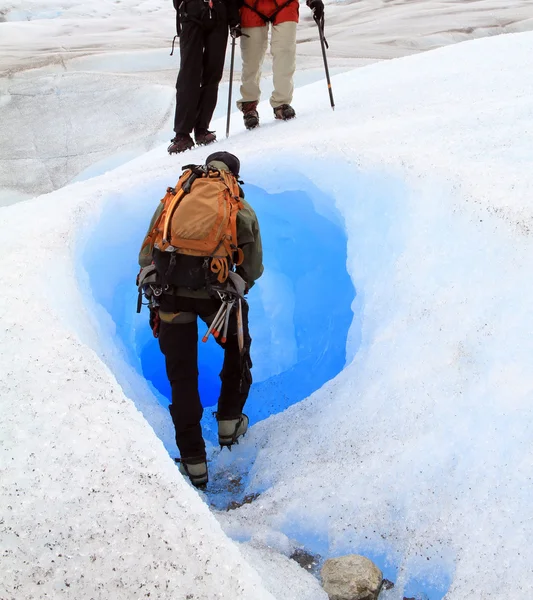 A man is about to enter to a tunnel naturally carved in a glacier Stock Picture