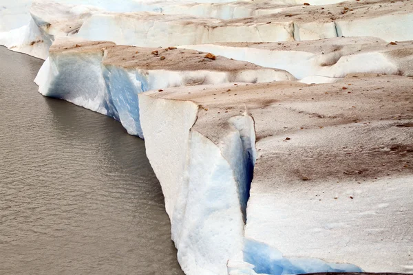 Il bordo di un ghiacciaio sporco si scioglie lentamente in un lago — Foto Stock