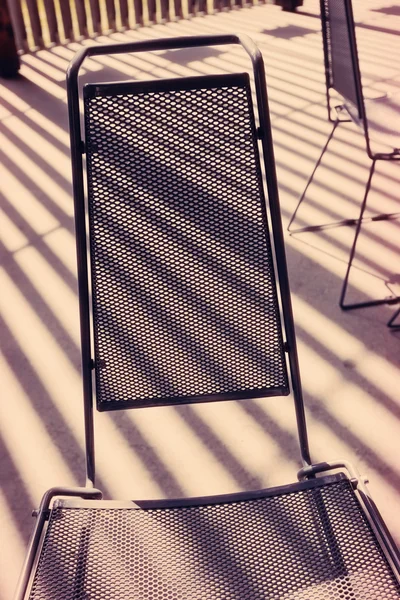 Chaise en maille métallique et rayures de lumière du soleil — Photo