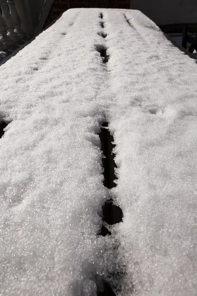 Minskande snö på ett picknickbord på en solig dag — Stockfoto